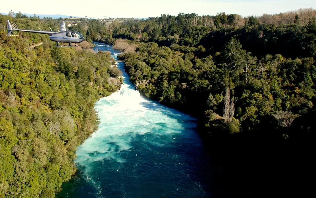 A helicopter above the turquoise Waikato River where it drops over Huka Falls