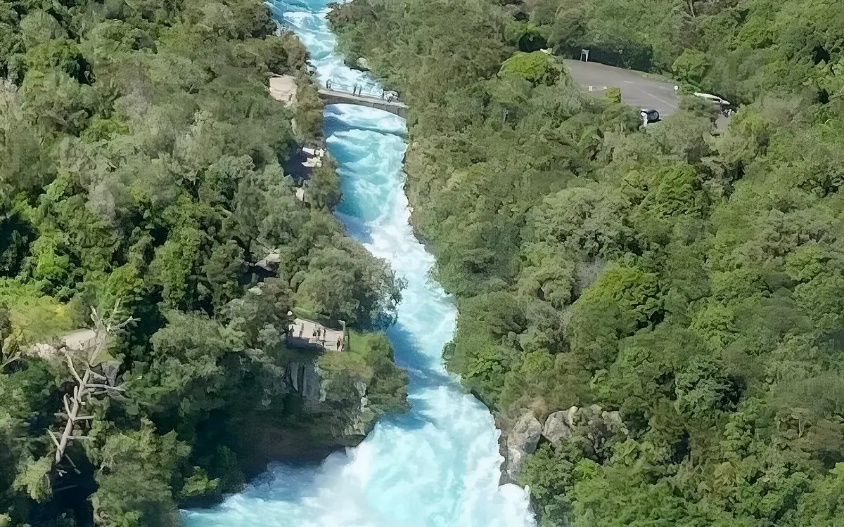 The turquoise Waikato River rushing through a narrow bush-lined gorge, seen from the air