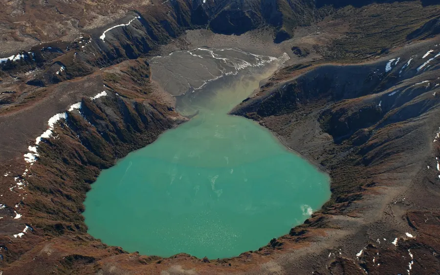 A helicopter on a snow slope beside a crater lake in the alpine plateau
